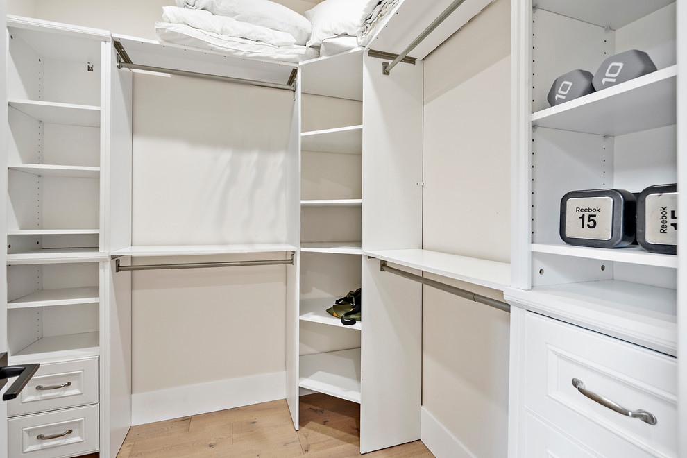 Modelo de armario vestidor unisex moderno con armarios con paneles empotrados, puertas de armario blancas, suelo de madera clara y suelo beige