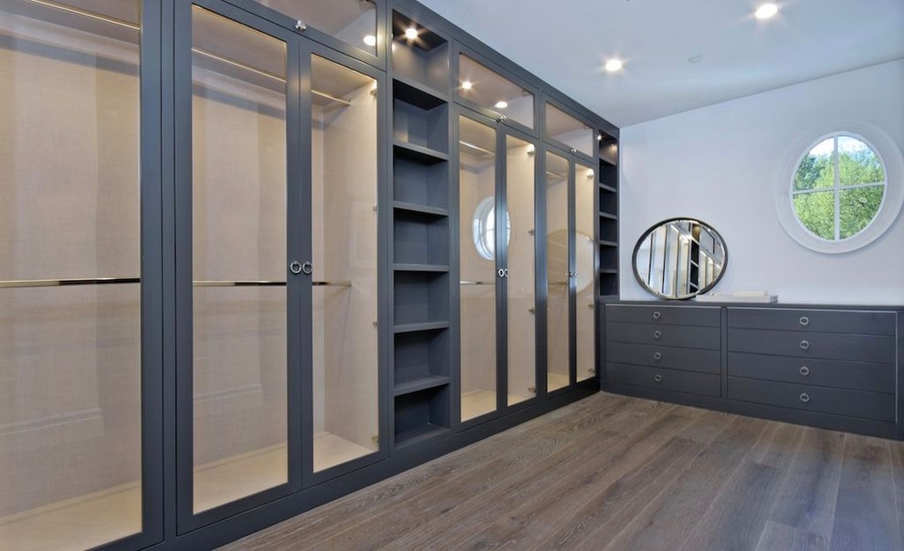 Exempel på ett mycket stort klassiskt walk-in-closet för könsneutrala, med mörkt trägolv, luckor med glaspanel, grå skåp och brunt golv
