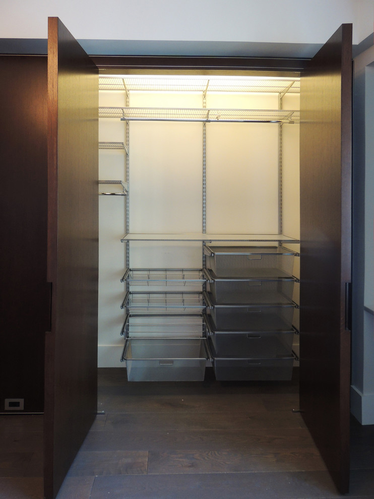 Walk-in closet - mid-sized contemporary gender-neutral medium tone wood floor walk-in closet idea in New York with flat-panel cabinets and dark wood cabinets