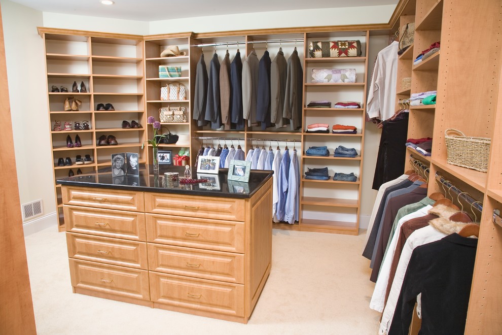 Diseño de armario vestidor unisex clásico grande con armarios con paneles con relieve, puertas de armario de madera clara, moqueta y suelo beige
