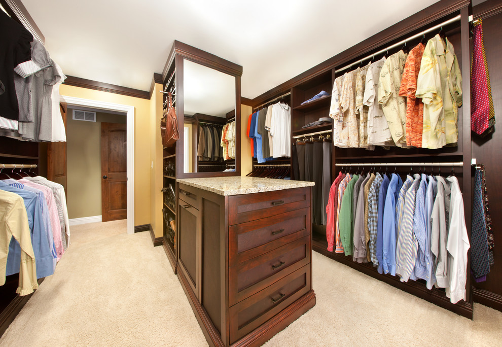 Large classic gender neutral walk-in wardrobe in Chicago with shaker cabinets, dark wood cabinets and carpet.