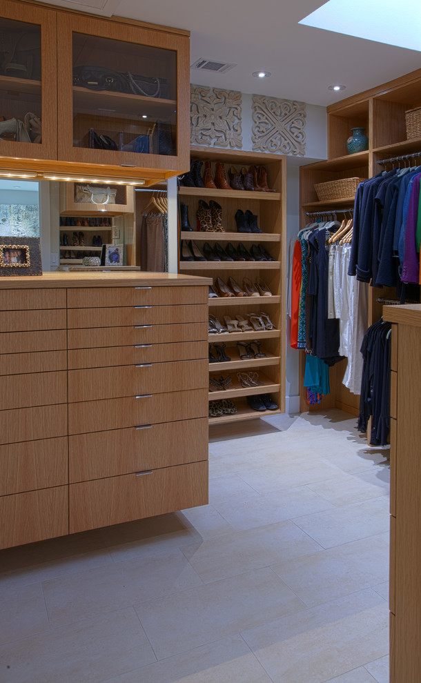 This is an example of a medium sized contemporary gender neutral walk-in wardrobe in Dallas with flat-panel cabinets, light wood cabinets and ceramic flooring.