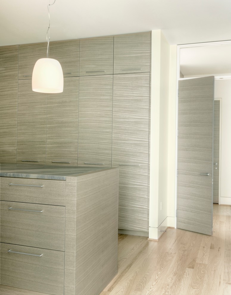Imagen de armario vestidor unisex moderno con armarios con paneles lisos, puertas de armario de madera clara y suelo de madera clara