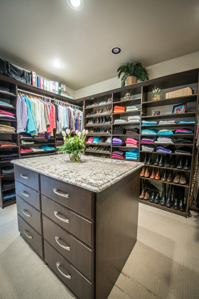 Large traditional gender neutral walk-in wardrobe in Other with flat-panel cabinets, dark wood cabinets and carpet.