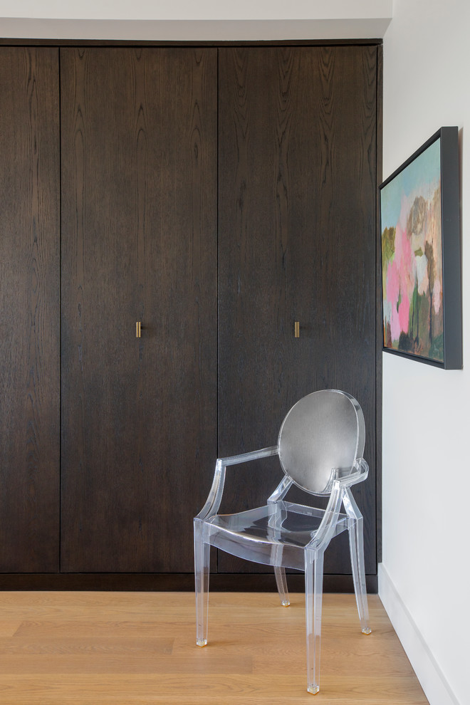 Diseño de armario y vestidor actual con armarios con paneles lisos, puertas de armario de madera en tonos medios y suelo de madera clara