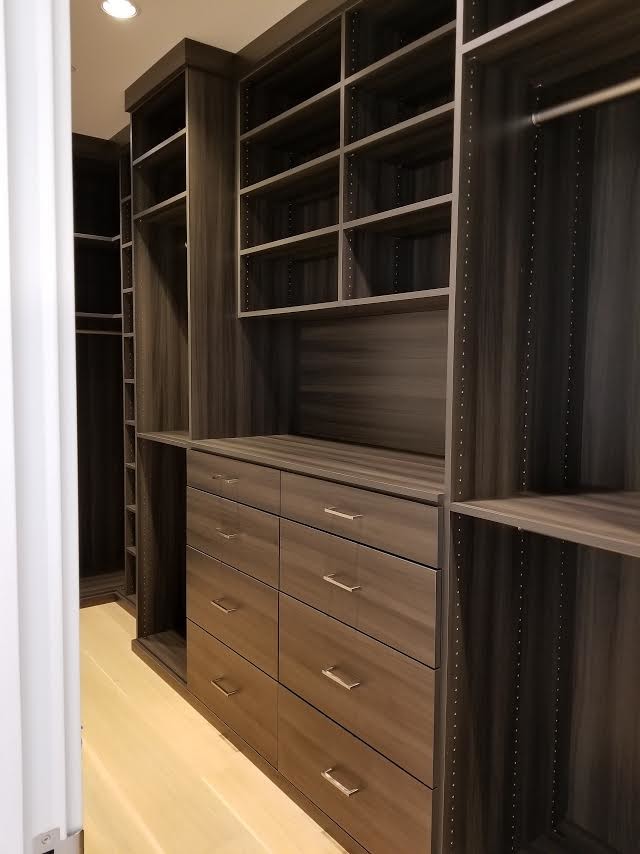 Inspiration for a large contemporary gender-neutral light wood floor and beige floor walk-in closet remodel in Seattle with flat-panel cabinets and dark wood cabinets
