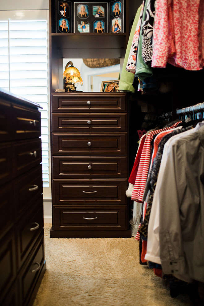 Diseño de armario vestidor unisex tradicional pequeño con armarios con paneles con relieve y puertas de armario de madera en tonos medios