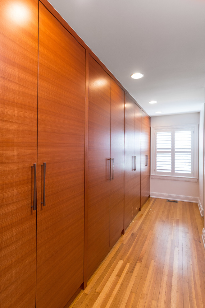 Diseño de vestidor unisex contemporáneo de tamaño medio con armarios estilo shaker, puertas de armario de madera oscura y suelo de madera clara