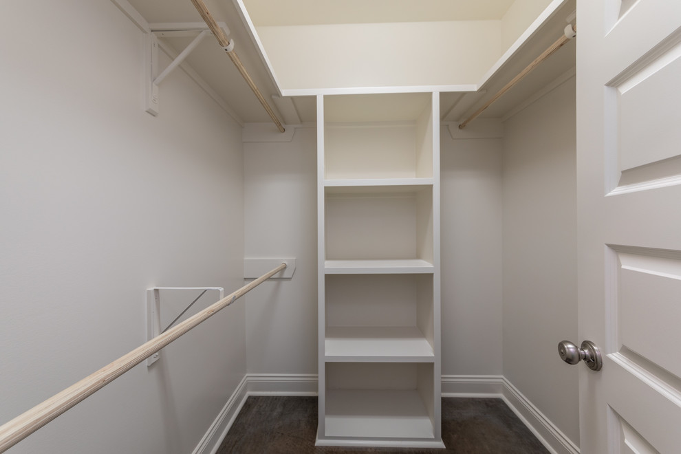 Mid-sized farmhouse gender-neutral concrete floor and brown floor walk-in closet photo in New Orleans