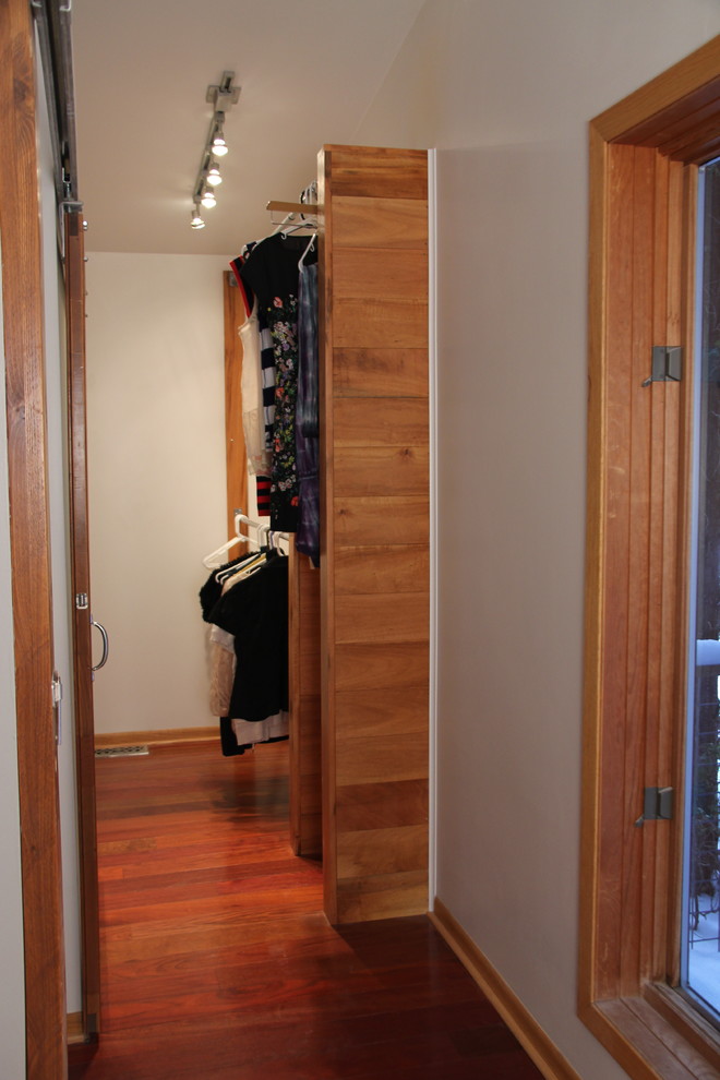 Foto de armario vestidor de mujer de estilo americano pequeño con puertas de armario de madera oscura y suelo de madera oscura