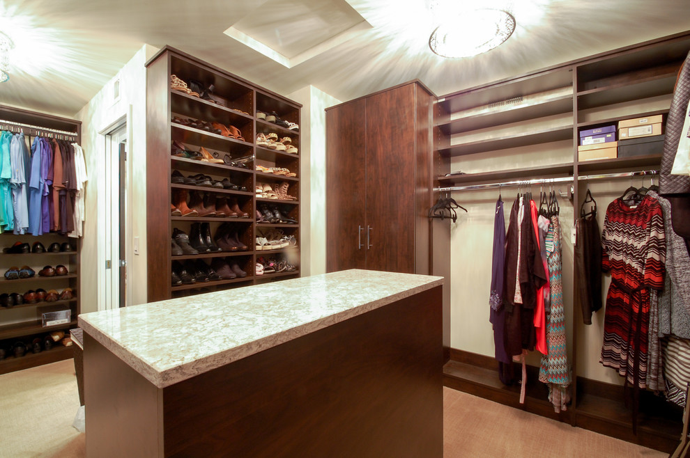 Example of a large trendy gender-neutral carpeted walk-in closet design in Minneapolis with flat-panel cabinets and dark wood cabinets