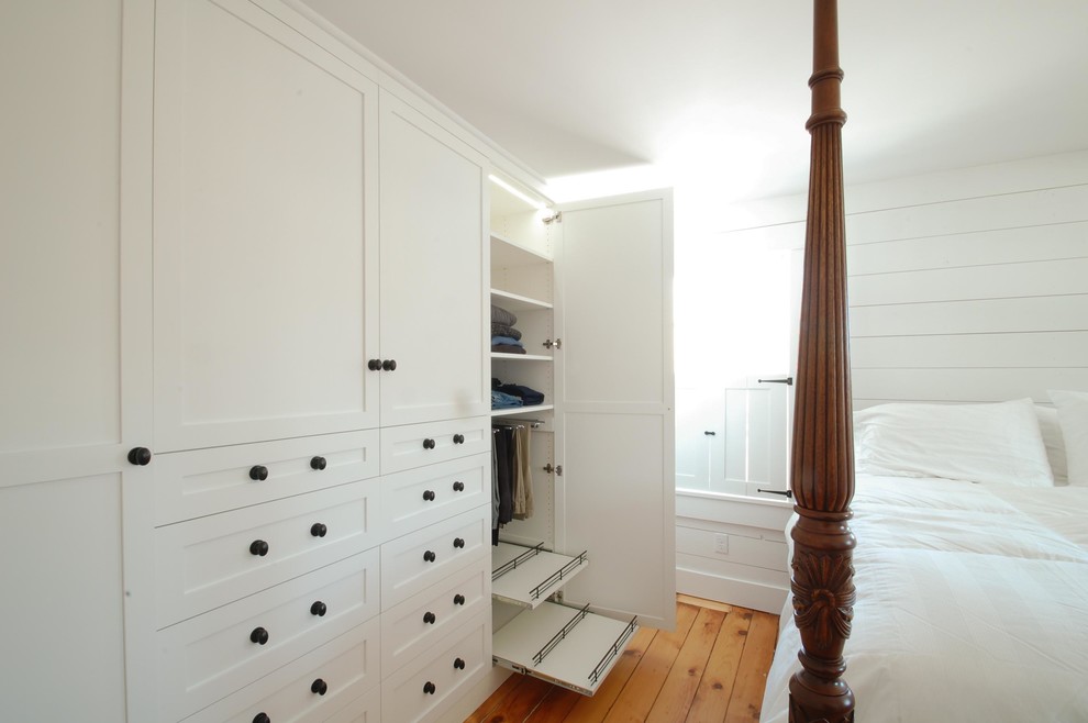 Diseño de vestidor unisex clásico de tamaño medio con armarios estilo shaker, puertas de armario blancas y suelo de madera en tonos medios