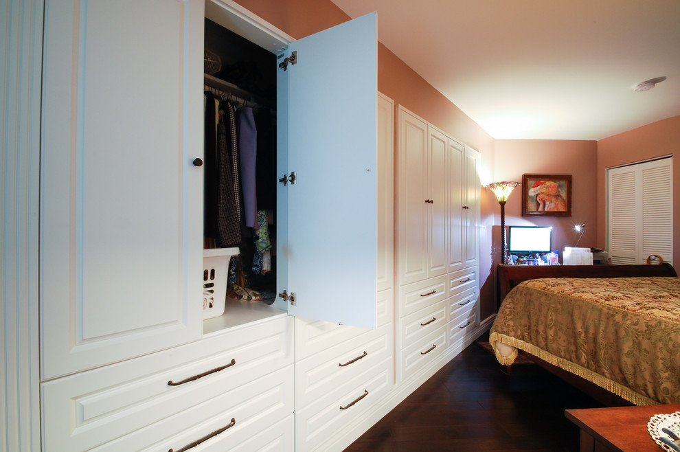 Imagen de armario de mujer clásico de tamaño medio con armarios con paneles con relieve, puertas de armario blancas y suelo de madera oscura