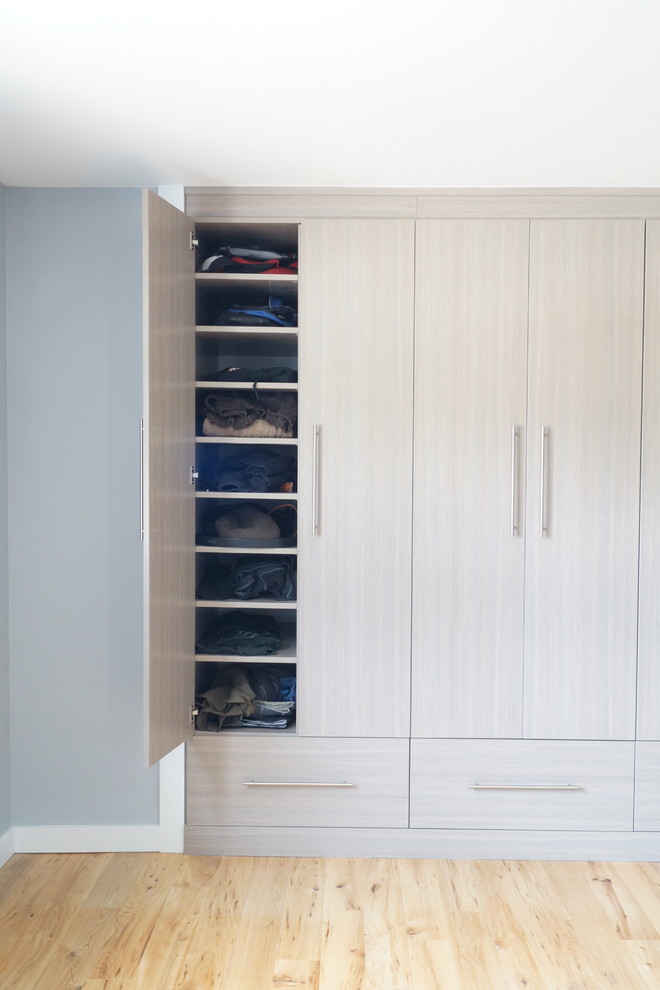 Imagen de armario unisex actual de tamaño medio con armarios con paneles lisos, puertas de armario grises y suelo de madera clara
