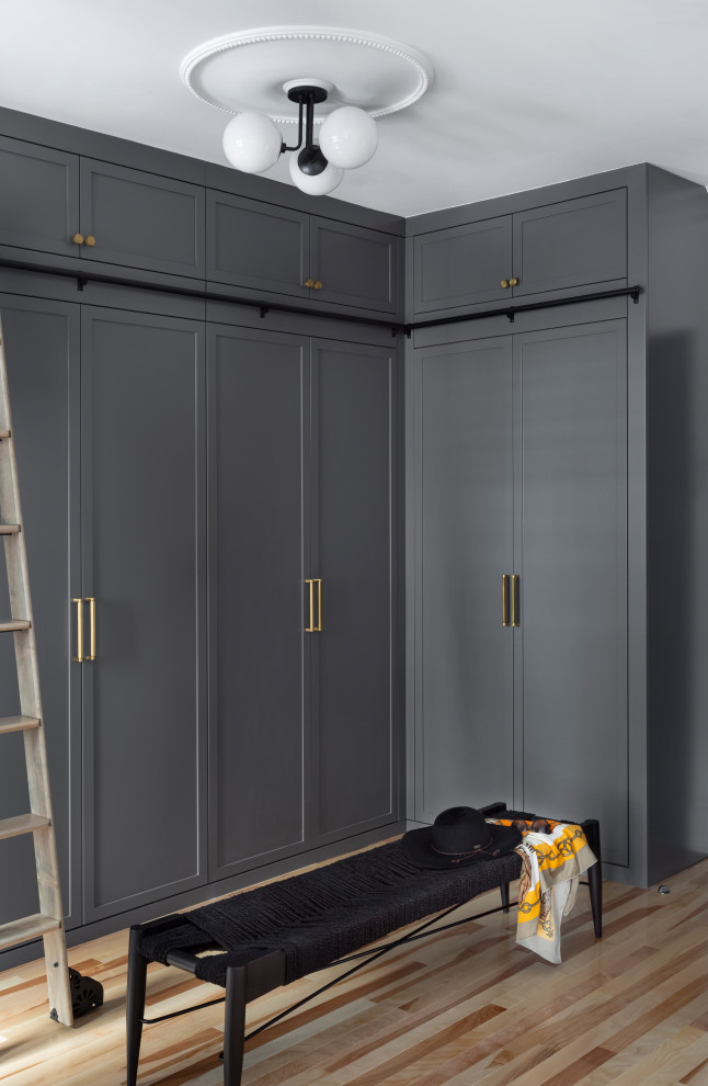 Diseño de armario vestidor unisex escandinavo grande con armarios estilo shaker, puertas de armario grises y suelo de madera clara