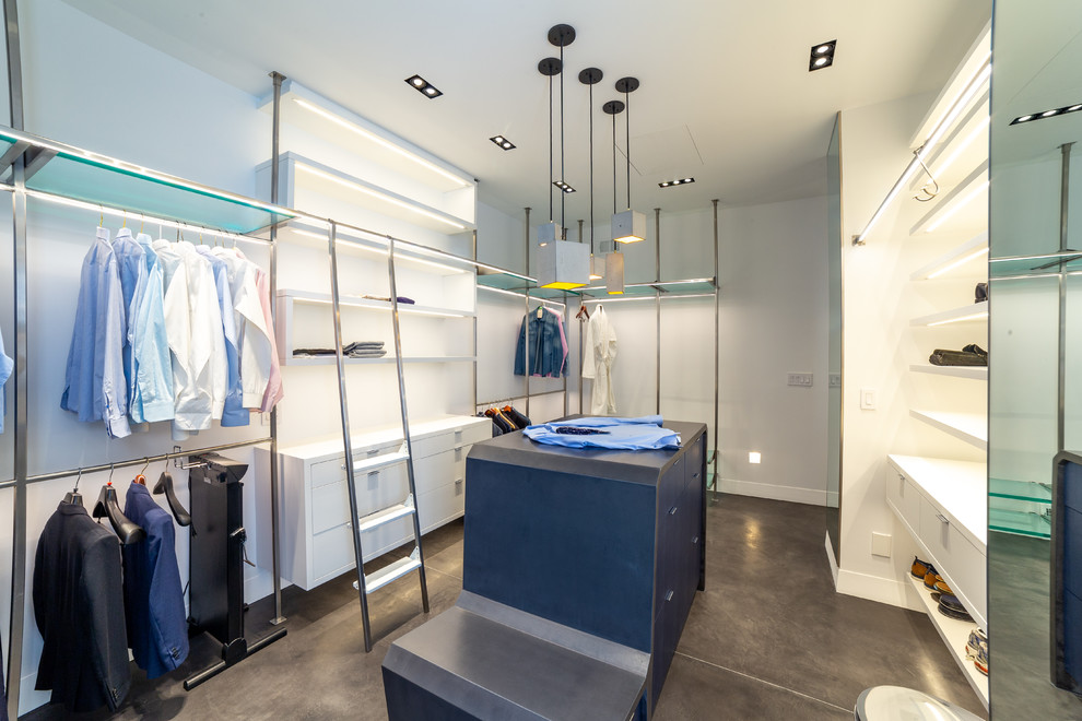 Idée de décoration pour un très grand dressing room minimaliste neutre avec un placard à porte plane, des portes de placard bleues, sol en béton ciré et un sol gris.
