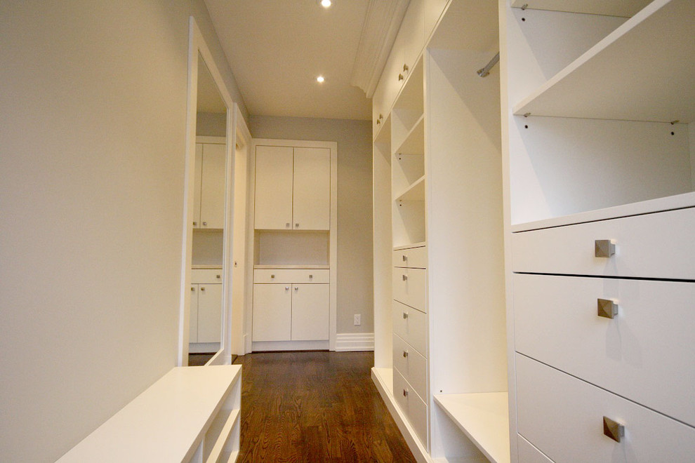 Inspiration for a large classic gender neutral walk-in wardrobe in Toronto with flat-panel cabinets, white cabinets and dark hardwood flooring.