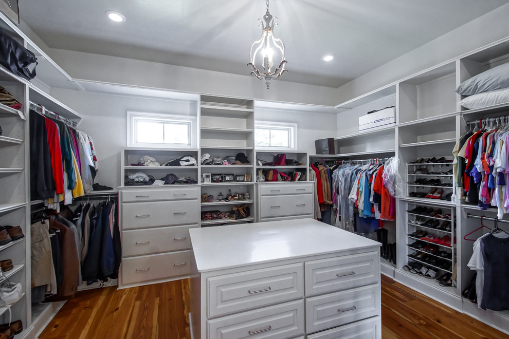 Ejemplo de armario vestidor unisex clásico renovado de tamaño medio con armarios con paneles con relieve, puertas de armario blancas y suelo de madera en tonos medios