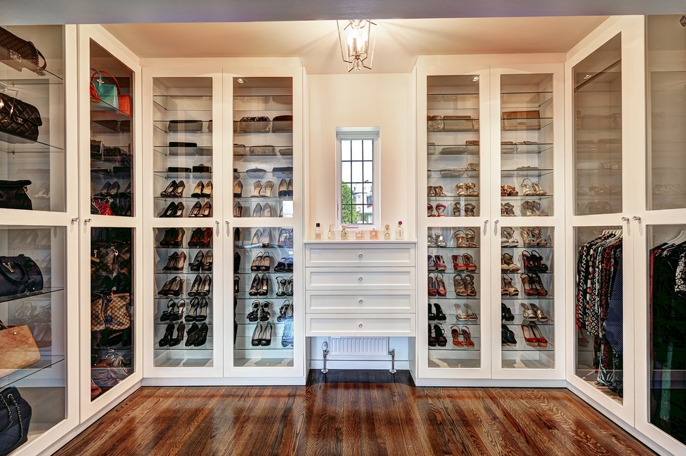 Inspiration for a large classic walk-in wardrobe for women in Montreal with glass-front cabinets, white cabinets and dark hardwood flooring.