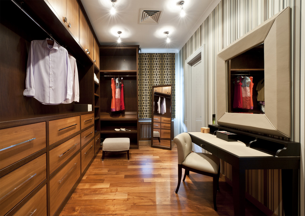 Cette image montre un dressing room traditionnel en bois brun neutre avec un placard à porte plane et un sol en bois brun.