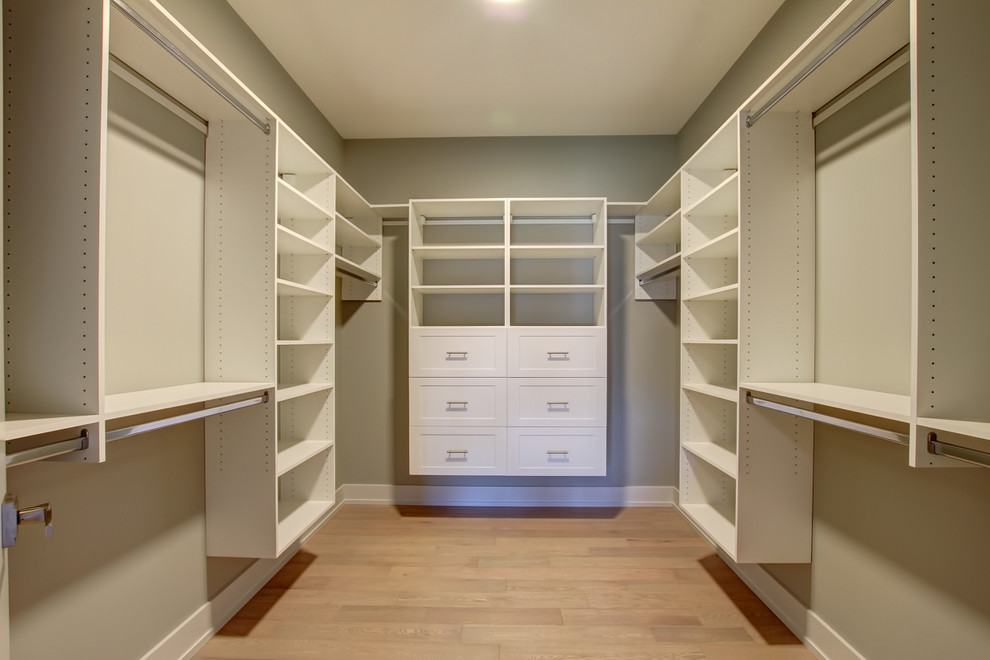 Diseño de armario vestidor unisex contemporáneo de tamaño medio con armarios estilo shaker, puertas de armario blancas, suelo de madera clara y suelo marrón