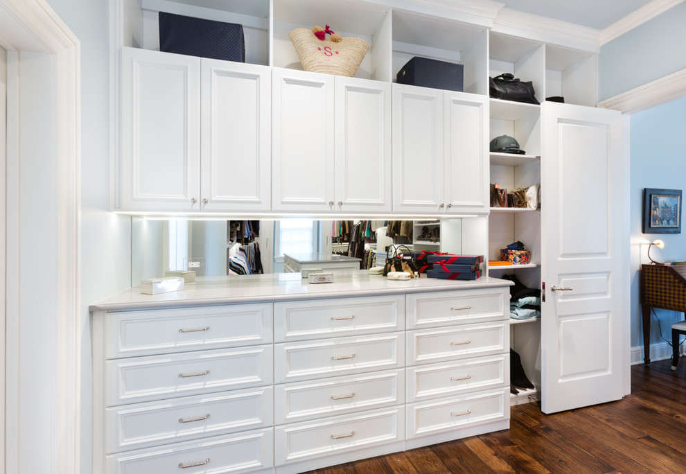 This is an example of a large classic walk-in wardrobe in Chicago with white cabinets, medium hardwood flooring and recessed-panel cabinets.