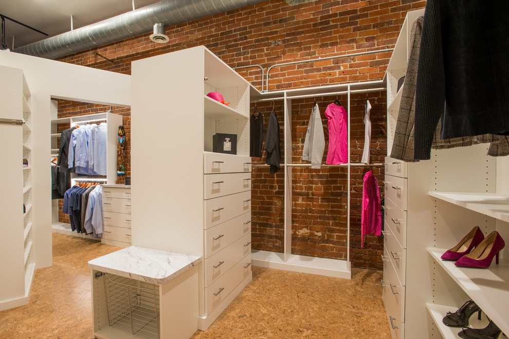 Ejemplo de armario vestidor unisex industrial con armarios abiertos, puertas de armario blancas, suelo de corcho y suelo beige
