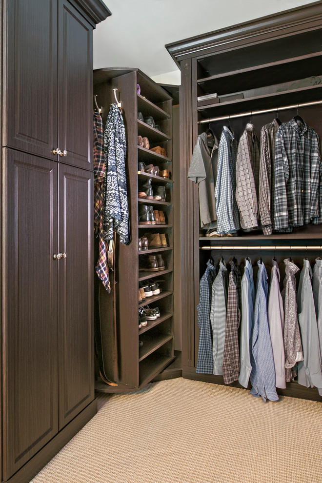 Large classic walk-in wardrobe for men in Chicago with raised-panel cabinets, medium wood cabinets and carpet.