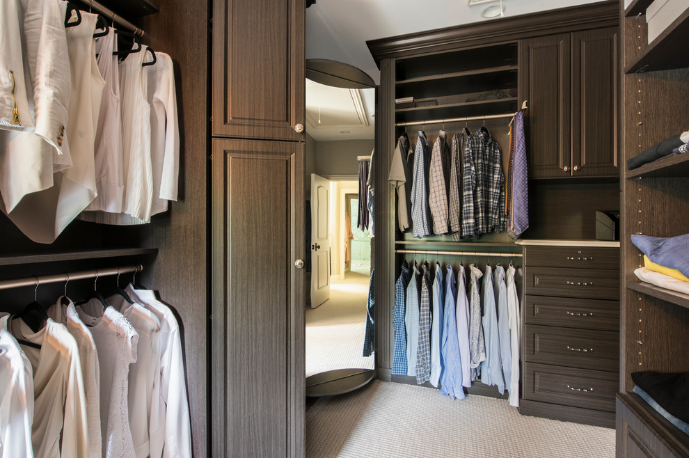 Diseño de armario vestidor unisex tradicional renovado grande con armarios con paneles con relieve, puertas de armario de madera oscura y moqueta