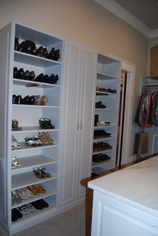 Foto de armario vestidor de mujer clásico grande con armarios con paneles con relieve, puertas de armario blancas y suelo de madera oscura