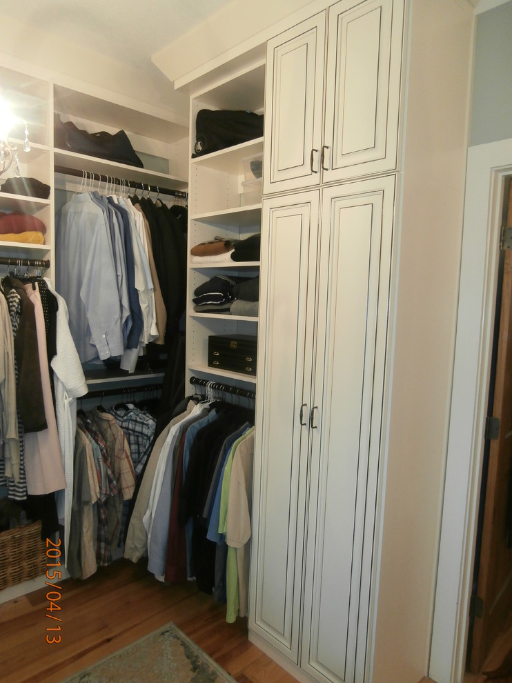 Imagen de vestidor de hombre tradicional de tamaño medio con armarios con paneles con relieve, puertas de armario con efecto envejecido y suelo de madera clara