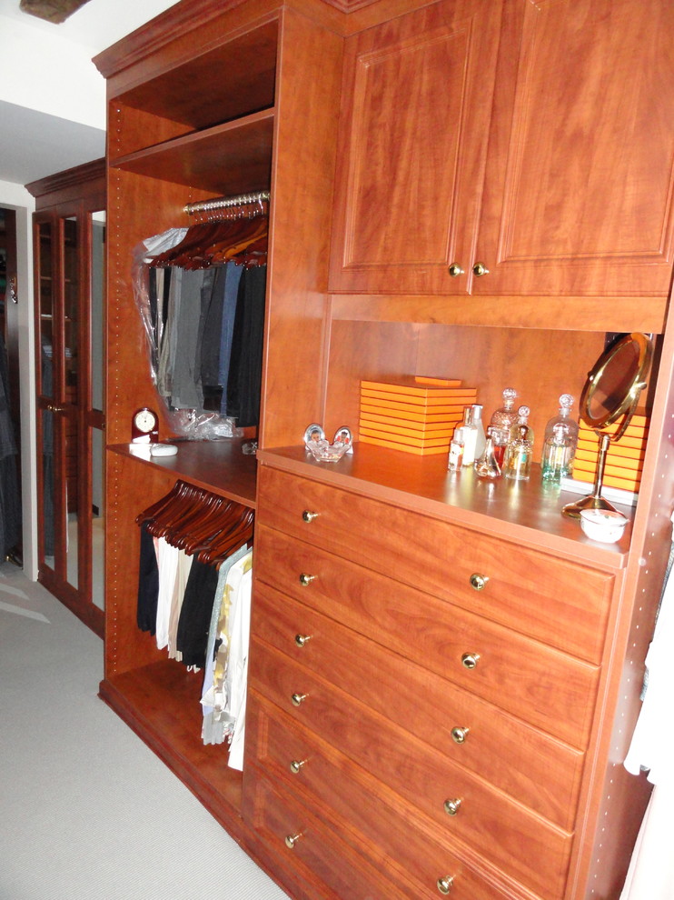 Ejemplo de armario vestidor unisex tradicional de tamaño medio con armarios con paneles con relieve, puertas de armario de madera oscura, moqueta y suelo gris