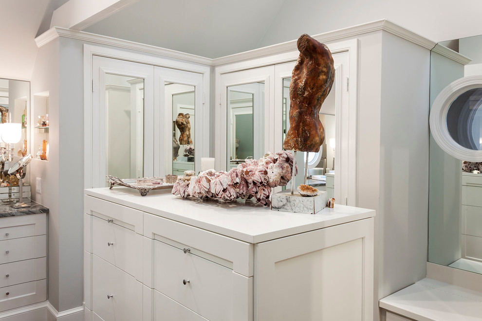 Cette image montre un grand dressing room traditionnel pour une femme avec un placard à porte shaker, des portes de placard blanches et un sol en bois brun.