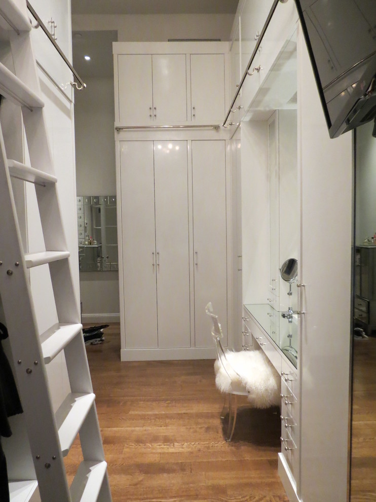 Inspiration for a large contemporary dressing room for women in New York with flat-panel cabinets, white cabinets and medium hardwood flooring.