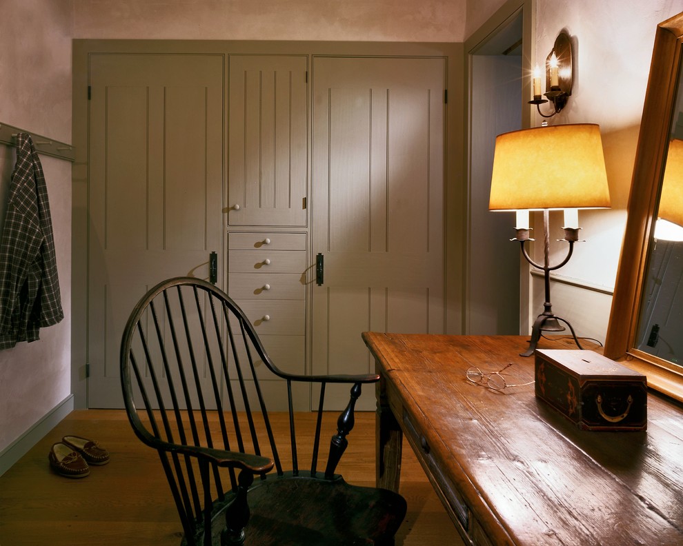Modelo de vestidor unisex de estilo de casa de campo grande con puertas de armario grises, suelo de madera en tonos medios y armarios con paneles lisos