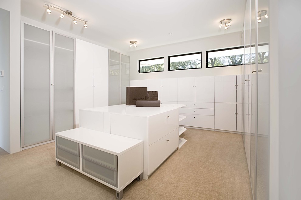 Exemple d'un dressing room tendance avec des portes de placard blanches et moquette.