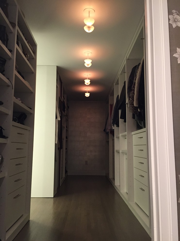 Photo of a large classic gender neutral walk-in wardrobe in New York with flat-panel cabinets, white cabinets and dark hardwood flooring.