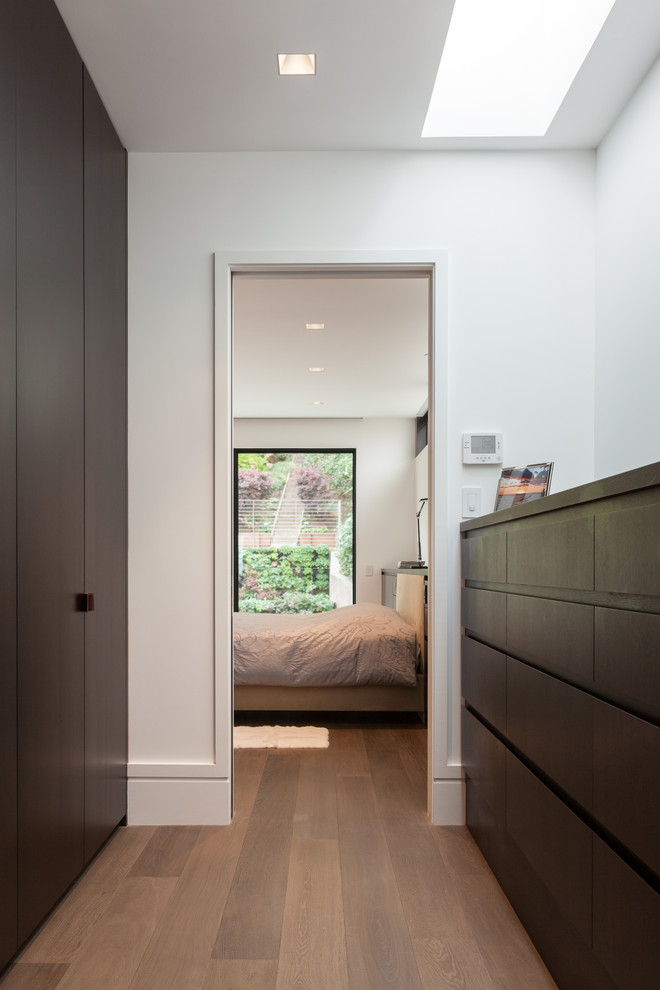 Foto de armario unisex minimalista de tamaño medio con armarios con paneles lisos, puertas de armario de madera en tonos medios y suelo de madera clara