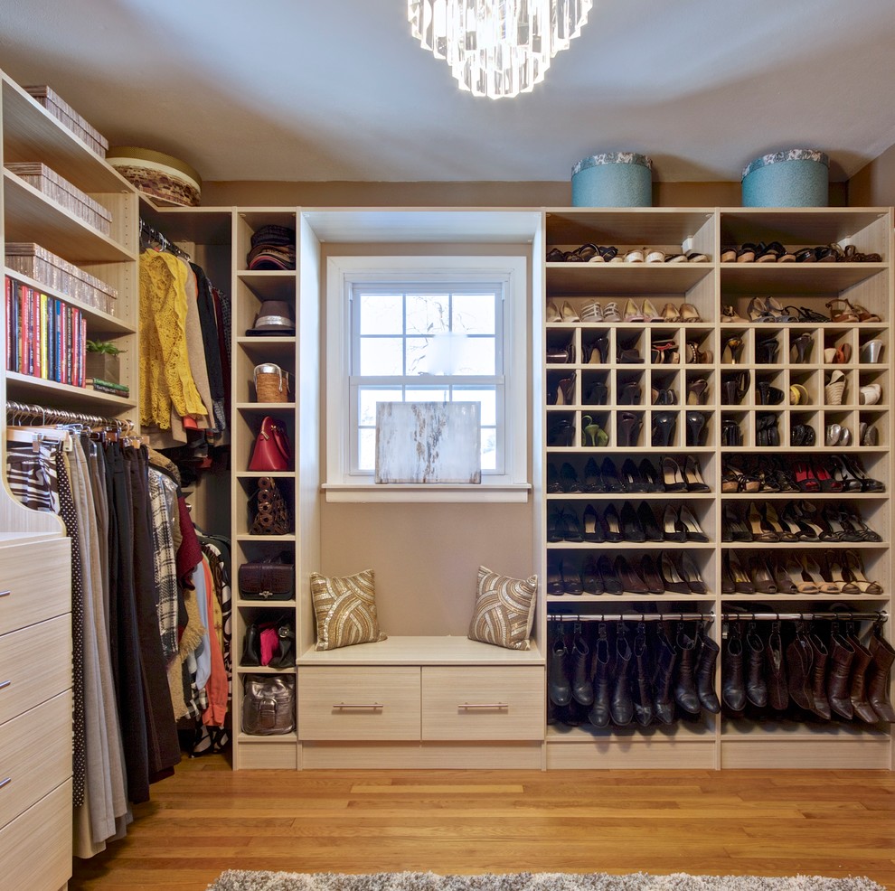 Ejemplo de armario vestidor de mujer moderno grande con armarios con paneles lisos, puertas de armario de madera clara y suelo de madera clara