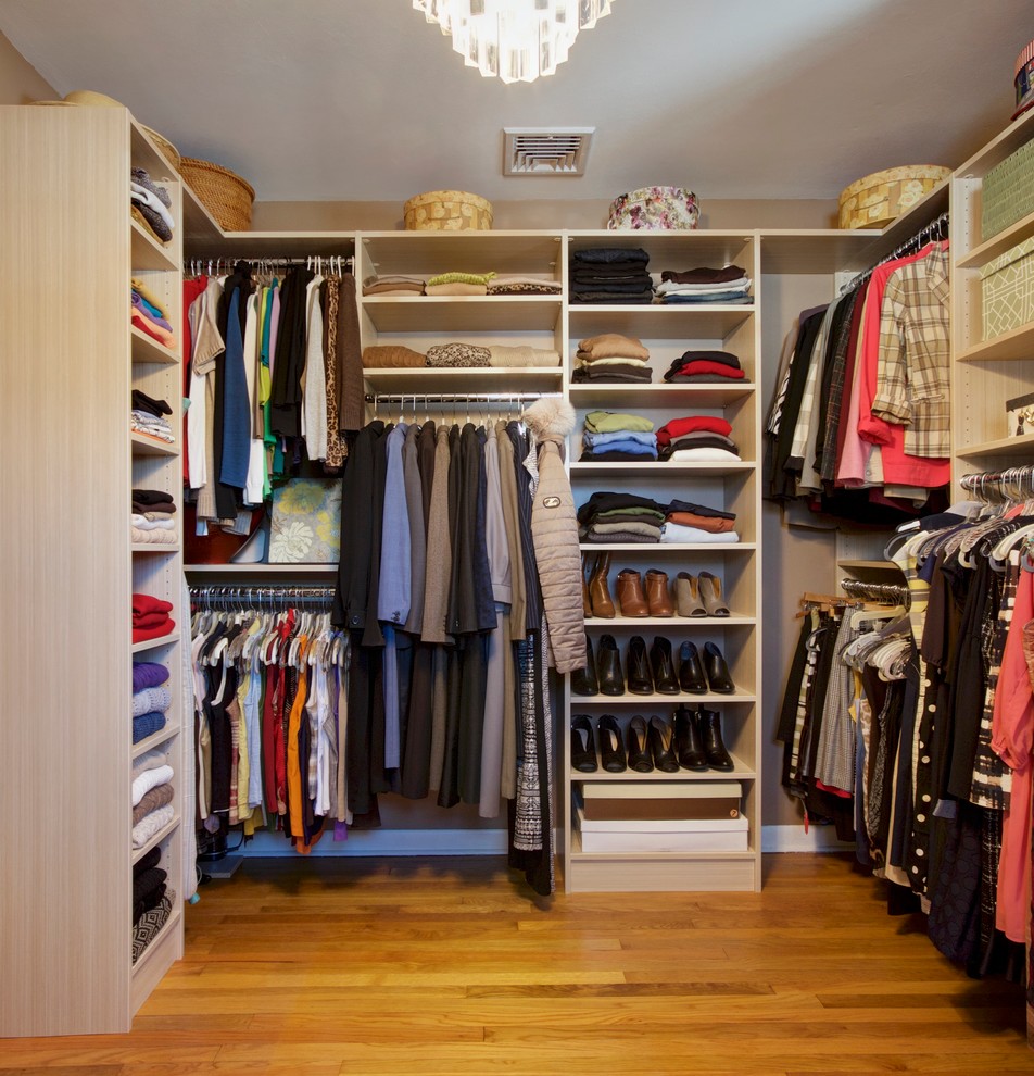 This is an example of a large modern walk-in wardrobe for women in Other with flat-panel cabinets, light wood cabinets and light hardwood flooring.