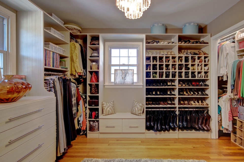 Modelo de armario vestidor de mujer minimalista grande con armarios con paneles lisos, puertas de armario de madera clara y suelo de madera clara