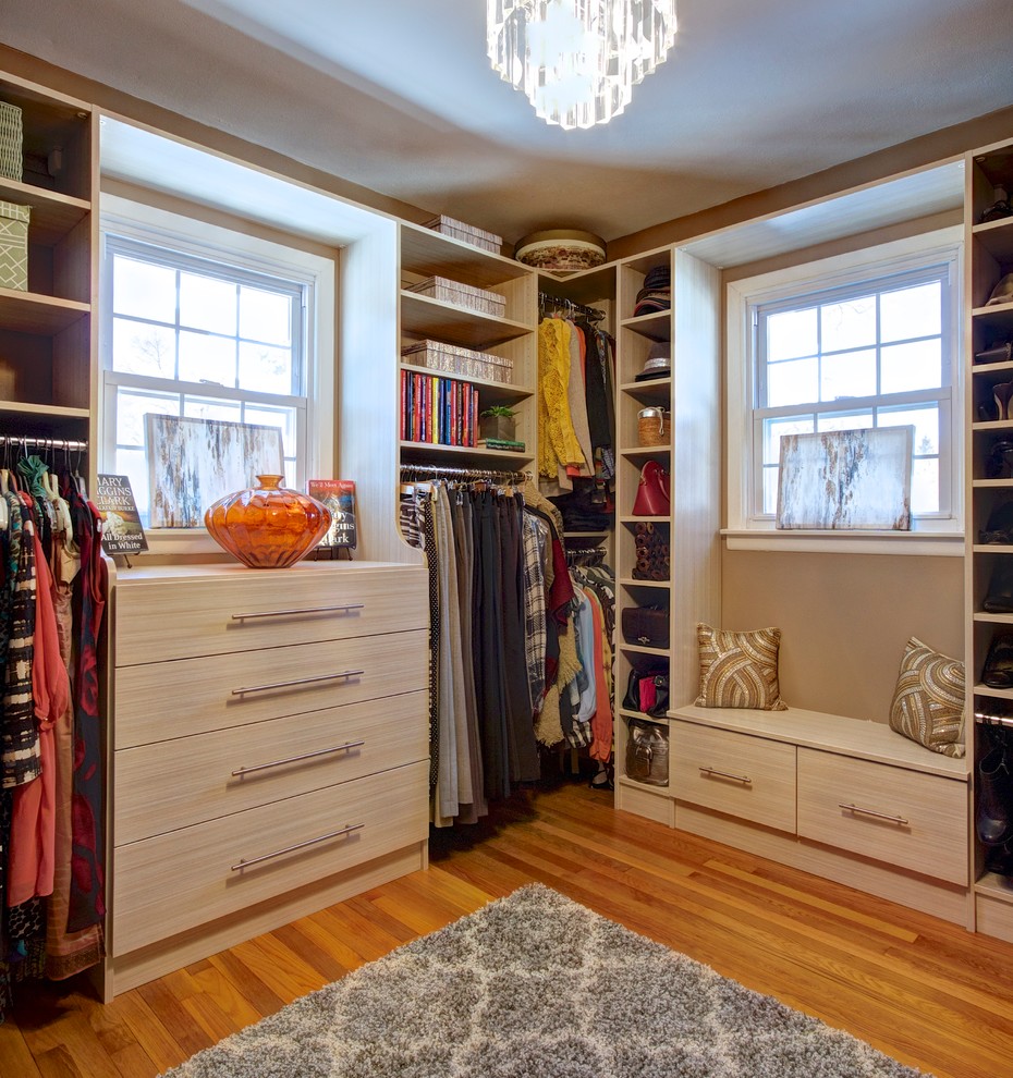 Photo of a large modern walk-in wardrobe for women in Other with flat-panel cabinets, light wood cabinets and light hardwood flooring.