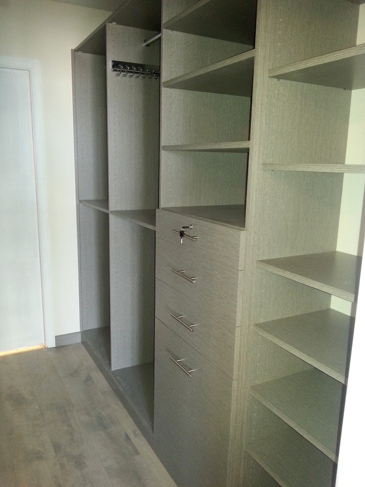 Foto de armario vestidor unisex actual de tamaño medio con armarios con paneles lisos, puertas de armario grises, suelo de madera clara y suelo beige