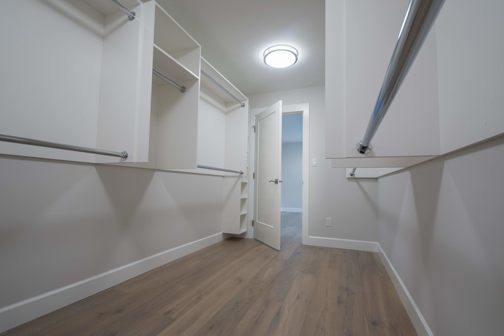 Idee per una cabina armadio unisex stile americano di medie dimensioni con ante bianche, pavimento in legno massello medio e pavimento marrone