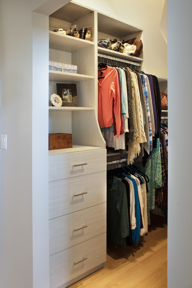 Small contemporary walk-in wardrobe for women in New York with flat-panel cabinets, light wood cabinets and light hardwood flooring.
