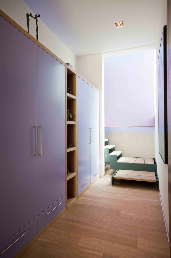 На фото: большая гардеробная комната унисекс в современном стиле с плоскими фасадами, светлым паркетным полом и синими фасадами с