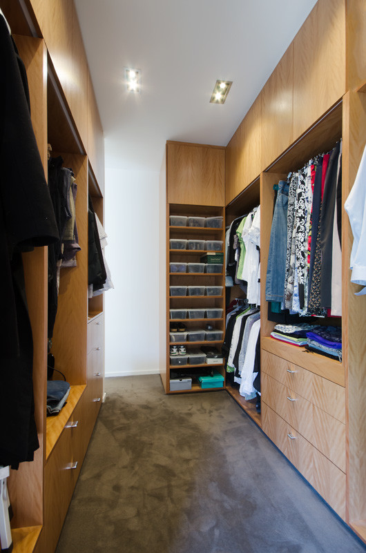 Diseño de armario vestidor unisex contemporáneo grande con armarios con paneles lisos, puertas de armario de madera oscura, moqueta y suelo marrón