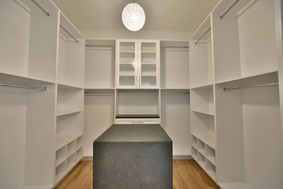 Foto de armario vestidor unisex tradicional renovado grande con armarios abiertos, puertas de armario blancas y suelo de madera clara