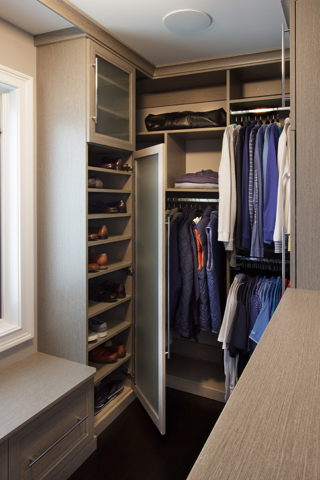Diseño de armario vestidor unisex tradicional renovado pequeño con armarios con paneles empotrados, puertas de armario grises y suelo de madera oscura