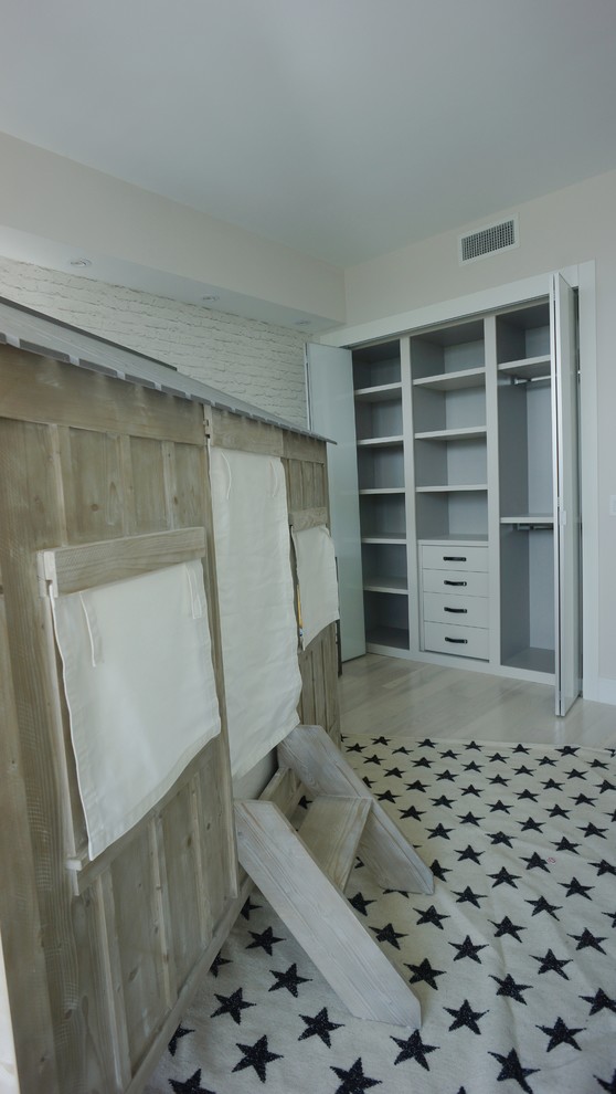 Cette image montre un dressing minimaliste de taille moyenne et neutre avec un placard à porte plane, des portes de placard blanches et parquet clair.